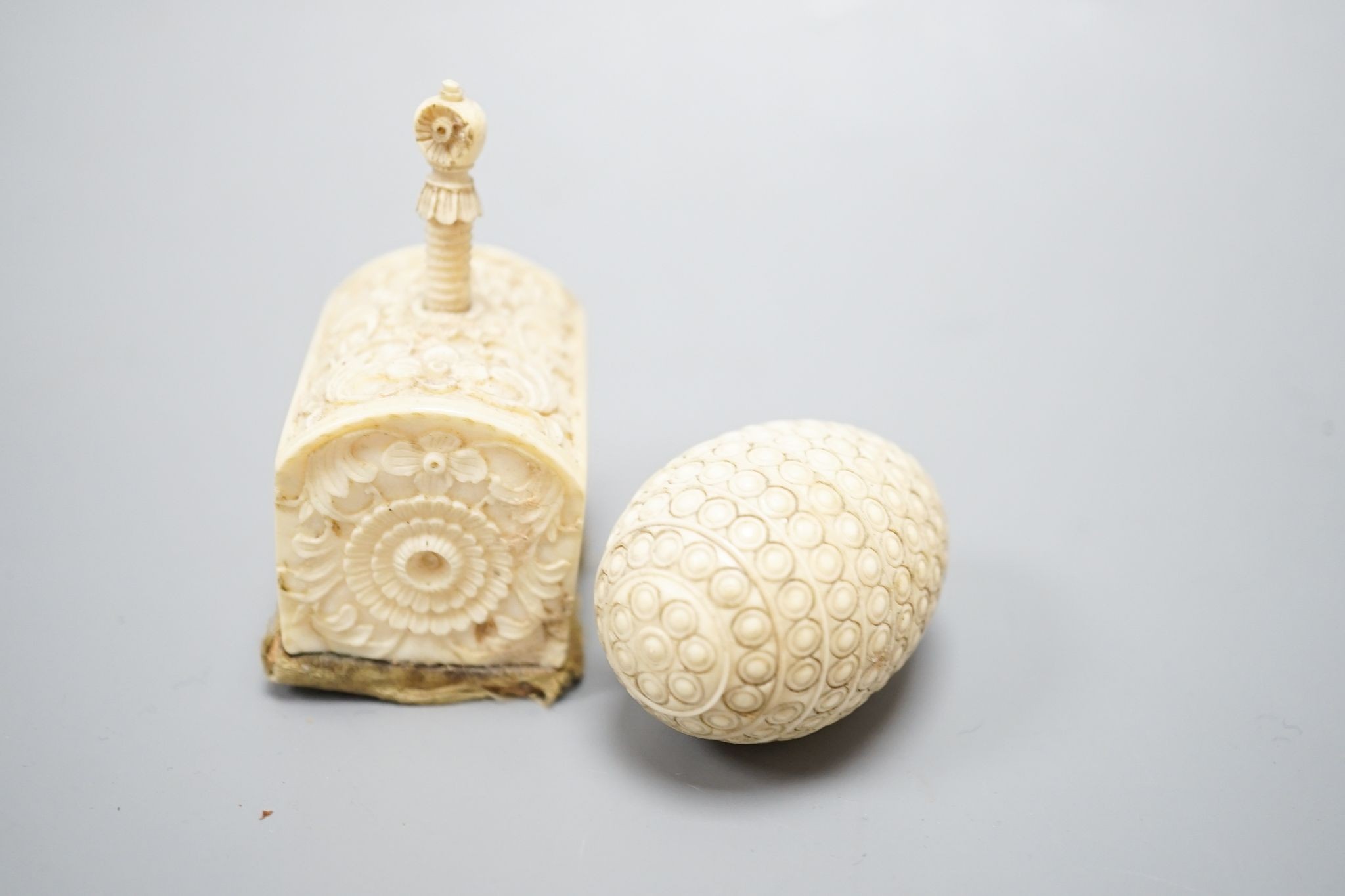 Ivory egg-shaped thread storage case and carved ivory needle-worker's table clamp, clamp, 6 cms high.